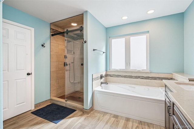 full bath featuring a garden tub, a stall shower, wood finished floors, and vanity