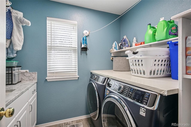 washroom featuring cabinet space, a textured wall, separate washer and dryer, wood finished floors, and baseboards