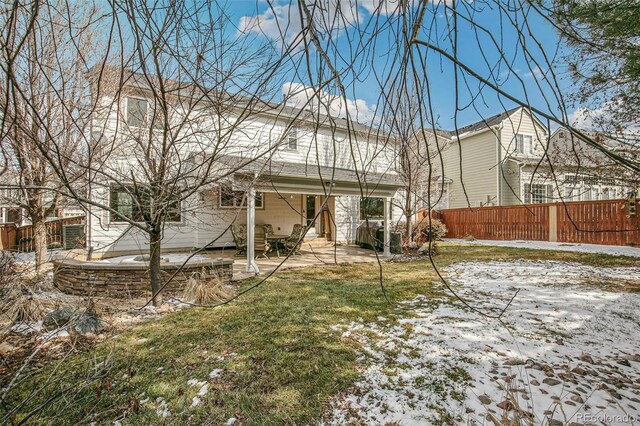 snow covered rear of property with a yard, a patio area, and fence