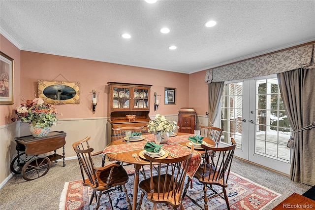 dining space featuring ornamental molding, light colored carpet, a textured ceiling, and french doors