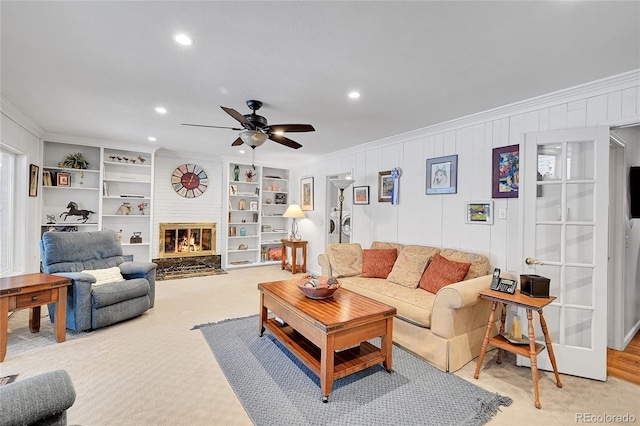 carpeted living room with crown molding, a fireplace, built in features, and ceiling fan