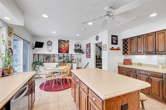 kitchen with a kitchen island, decorative backsplash, stainless steel dishwasher, light tile patterned floors, and ceiling fan