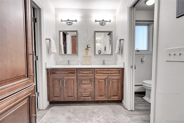 bathroom with vanity, hardwood / wood-style floors, toilet, and baseboard heating