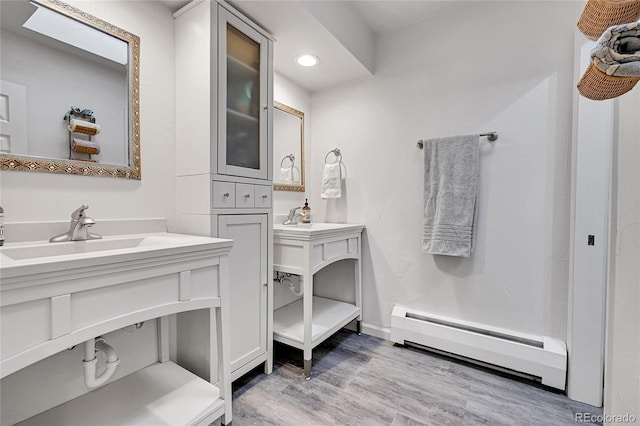 bathroom with wood-type flooring, vanity, and a baseboard heating unit