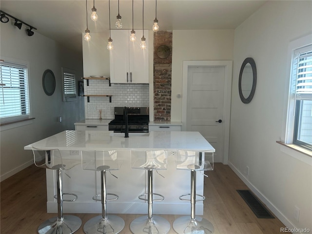 kitchen featuring black gas stove, backsplash, visible vents, and a healthy amount of sunlight