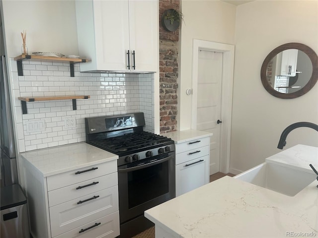 kitchen with light stone counters, stainless steel range with gas cooktop, a sink, and open shelves