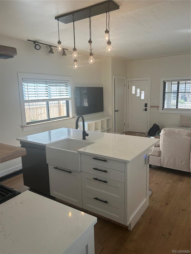 kitchen featuring dark wood finished floors, a center island with sink, open floor plan, white cabinetry, and a sink