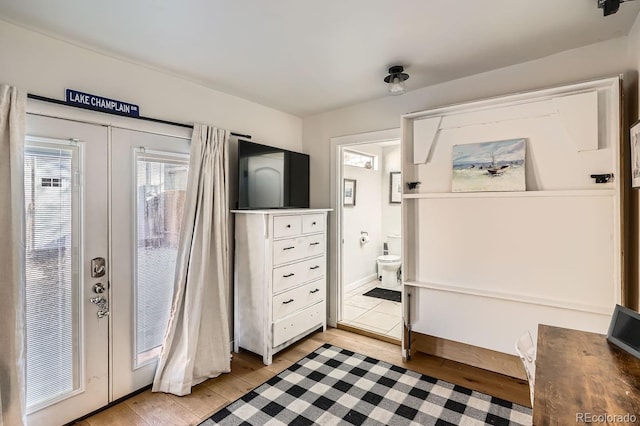 bedroom with french doors, ensuite bath, and light wood-style floors