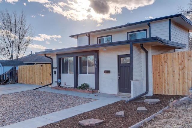 view of front of home with brick siding and fence