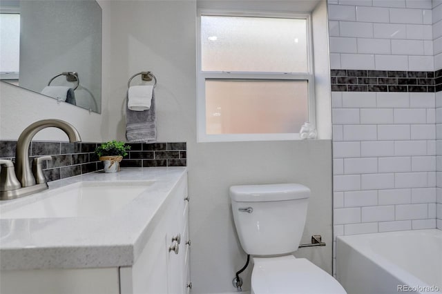 full bathroom featuring vanity, tiled shower / bath, decorative backsplash, and toilet