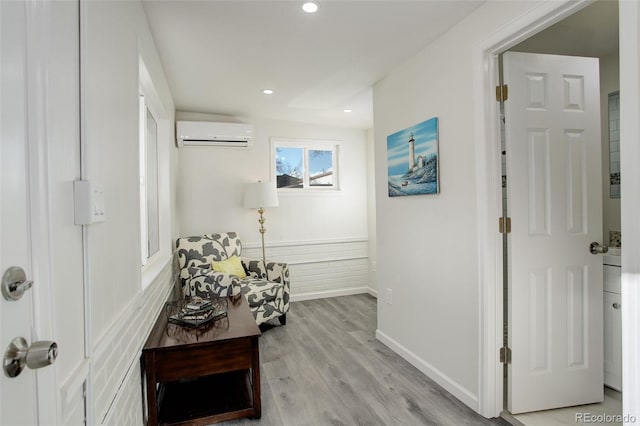 hallway featuring a wall unit AC and light hardwood / wood-style flooring