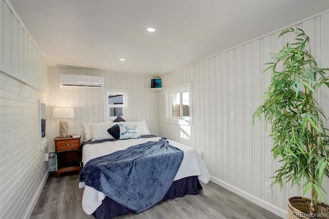 bedroom with hardwood / wood-style flooring and a wall unit AC