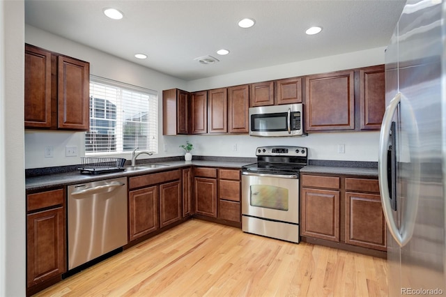 25812 E Cedar Pl, Aurora, CO 80018 - kitchen with appliances with stainless steel finishes, a sink, dark countertops, light wood finished floors, and recessed lighting
