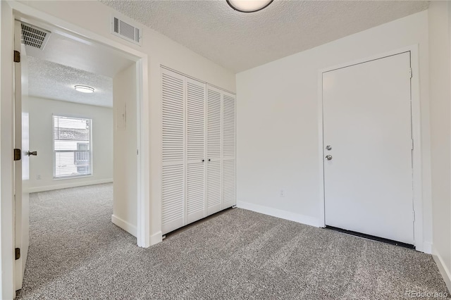 unfurnished bedroom with carpet floors, a closet, and a textured ceiling