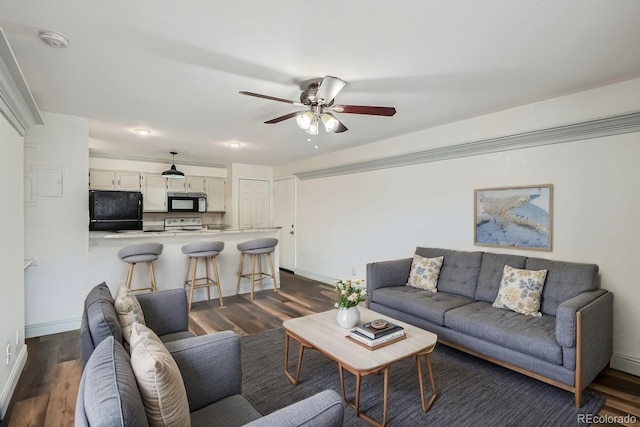 living area featuring baseboards, ceiling fan, and dark wood-style flooring