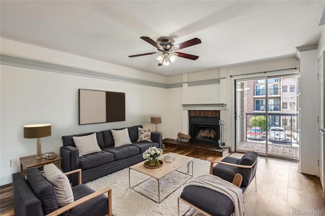 living room with a ceiling fan, wood finished floors, and a tile fireplace