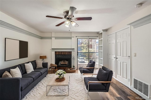 living area with visible vents, ceiling fan, wood finished floors, and a fireplace