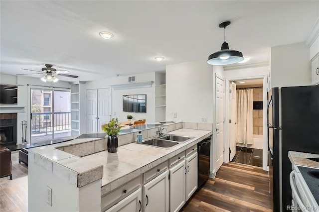 kitchen with black dishwasher, a peninsula, a sink, and dark wood-style flooring