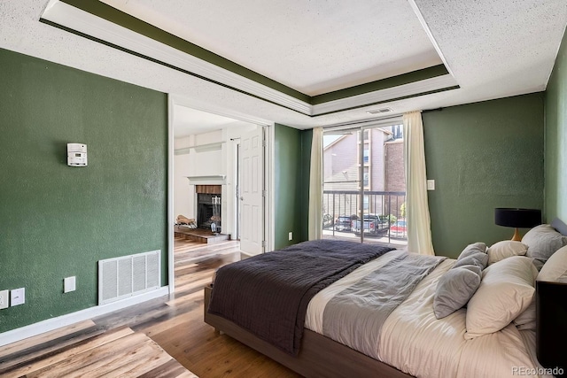 bedroom with visible vents, a raised ceiling, a textured wall, and access to outside