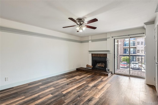 unfurnished living room featuring baseboards, ceiling fan, wood finished floors, and a fireplace
