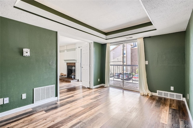 empty room with a tray ceiling, visible vents, and a textured wall