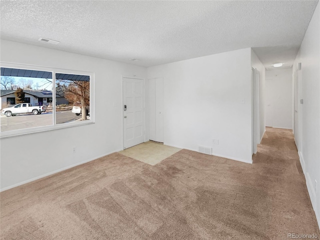 carpeted empty room featuring a textured ceiling