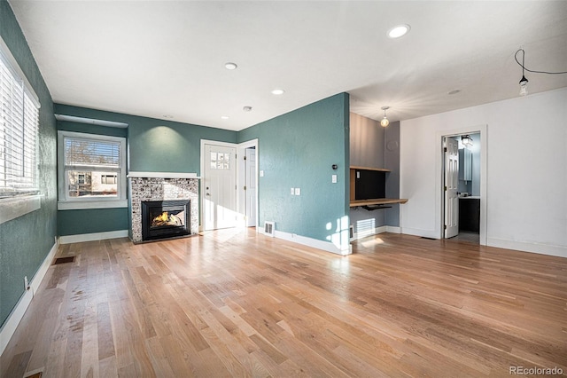 unfurnished living room featuring a stone fireplace and hardwood / wood-style floors