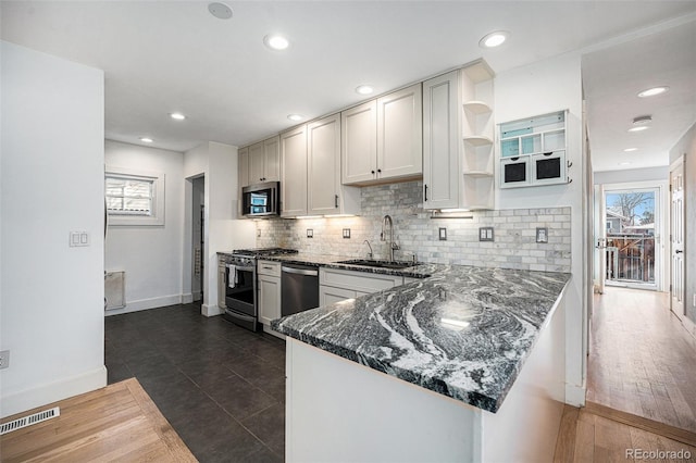 kitchen featuring appliances with stainless steel finishes, sink, dark stone countertops, white cabinets, and kitchen peninsula