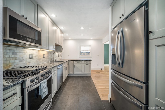 kitchen featuring dark stone countertops, sink, backsplash, and stainless steel appliances