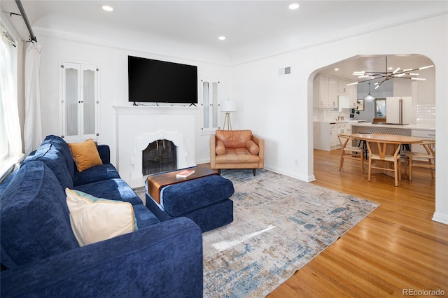 1661 Oneida St, Denver, CO 80220 - living room featuring arched walkways, light wood-style floors, a fireplace, recessed lighting, and a chandelier