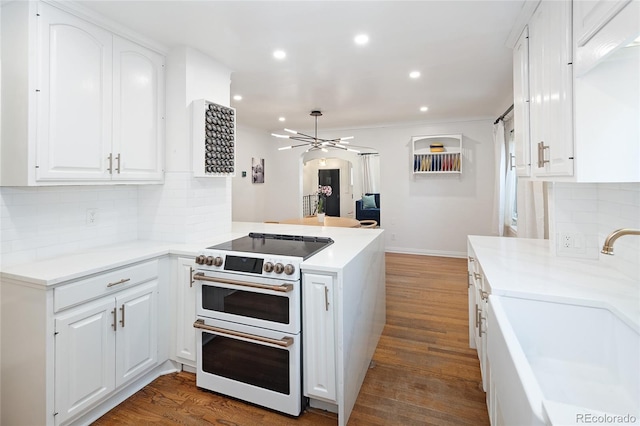 1661 Oneida St, Denver, CO 80220 - kitchen with double oven range, wood finished floors, tasteful backsplash, white cabinets, and recessed lighting