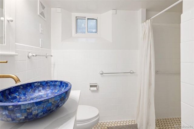 1661 Oneida St, Denver, CO 80220 - bathroom with tile walls, a tile shower, tile patterned floors, and a wainscoted wall