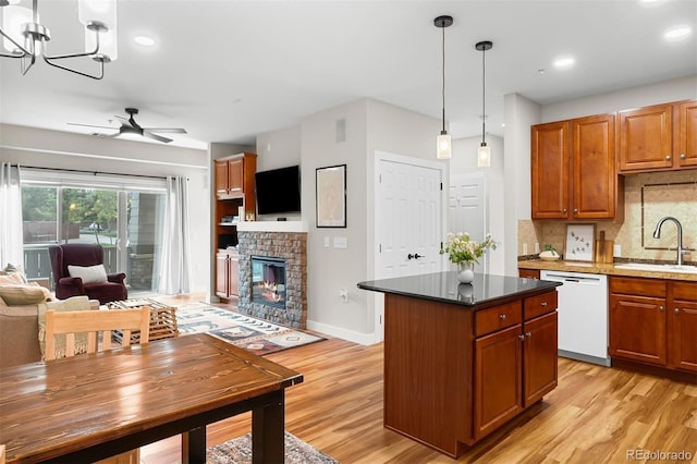 16600 Las Ramblas Ln Unit A, Parker, CO 80134 - kitchen with dishwasher, light wood-type flooring, ceiling fan, backsplash, and a glass covered fireplace