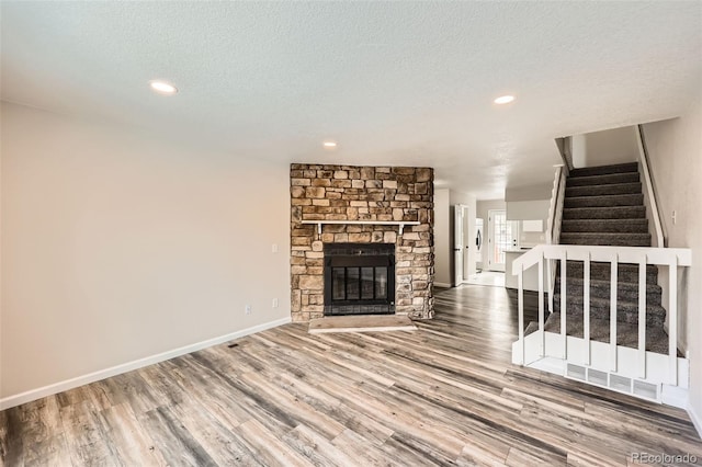 unfurnished living room featuring hardwood / wood-style flooring, a fireplace, and a textured ceiling