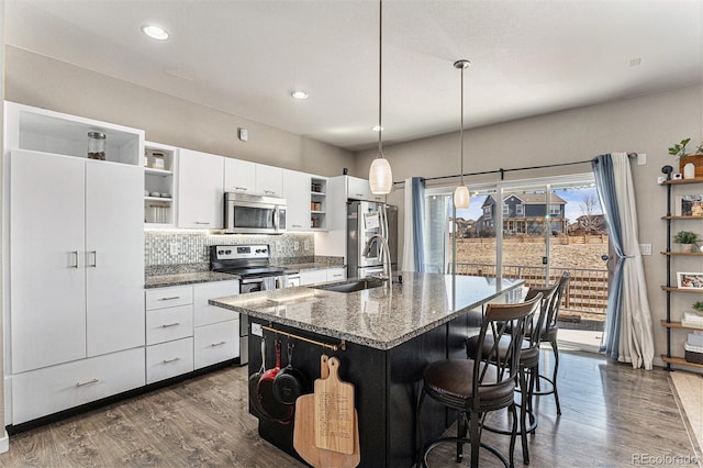 10796 Truckee Cir, Commerce City, CO 80022 - kitchen with open shelves, appliances with stainless steel finishes, a sink, white cabinetry, and a center island with sink