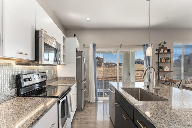 10796 Truckee Cir, Commerce City, CO 80022 - kitchen with appliances with stainless steel finishes, a sink, white cabinets, tasteful backsplash, and hanging light fixtures