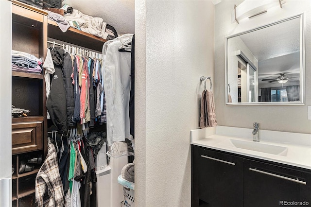 10796 Truckee Cir, Commerce City, CO 80022 - bathroom with a spacious closet, a textured wall, vanity, and ceiling fan