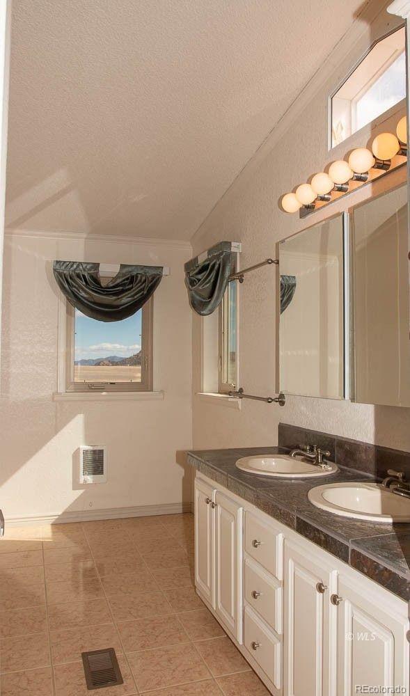 bathroom featuring crown molding, tile floors, dual bowl vanity, and a textured ceiling