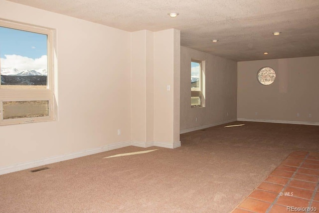 unfurnished room featuring a textured ceiling, a wealth of natural light, and tile floors