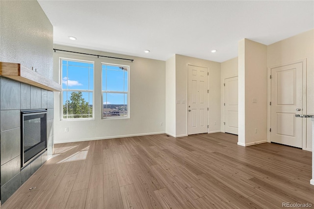 unfurnished living room featuring hardwood / wood-style flooring and a tiled fireplace