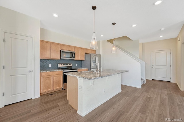 kitchen featuring decorative backsplash, a center island with sink, appliances with stainless steel finishes, and light wood-type flooring