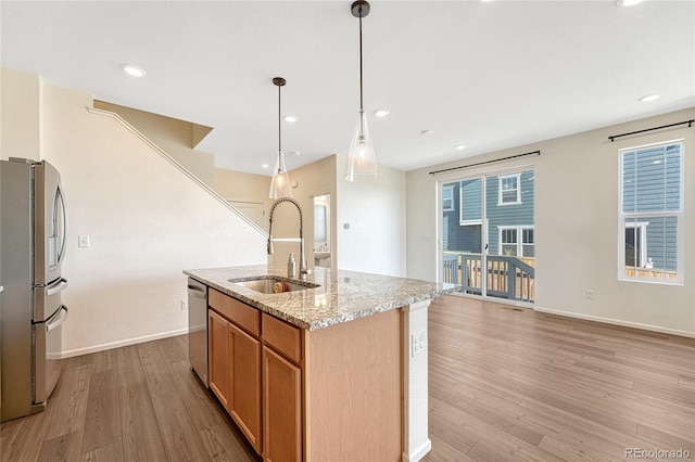 kitchen featuring stainless steel appliances, light hardwood / wood-style flooring, sink, and an island with sink