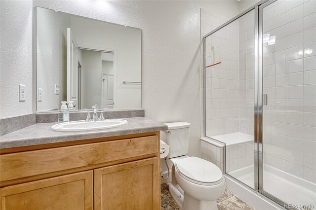 bathroom with a shower with door, tile patterned floors, toilet, and vanity