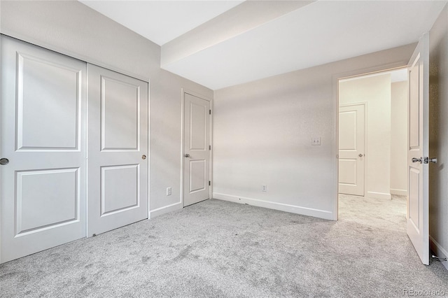 unfurnished bedroom featuring a closet and light colored carpet