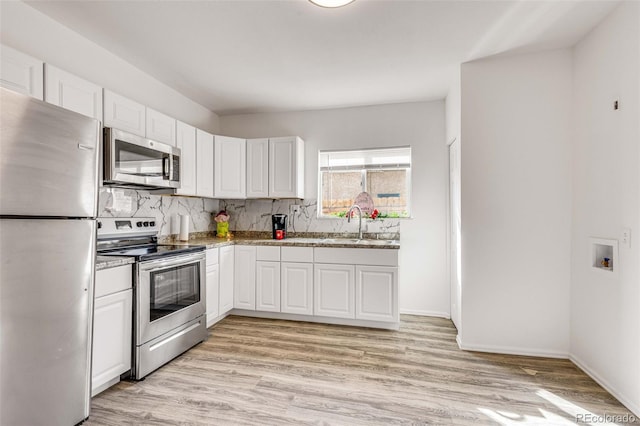 kitchen with sink, appliances with stainless steel finishes, white cabinetry, tasteful backsplash, and light wood-type flooring