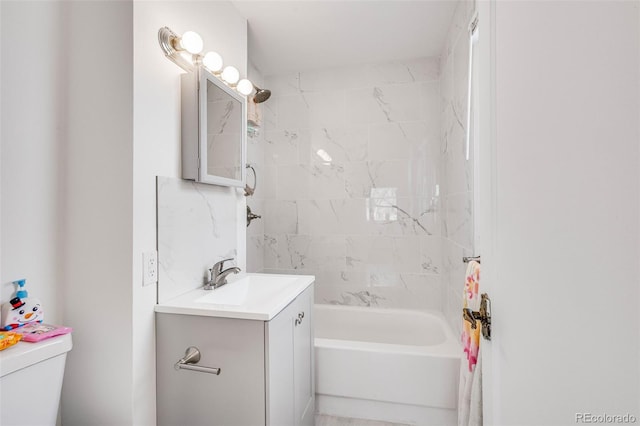 full bathroom featuring tiled shower / bath, vanity, and toilet