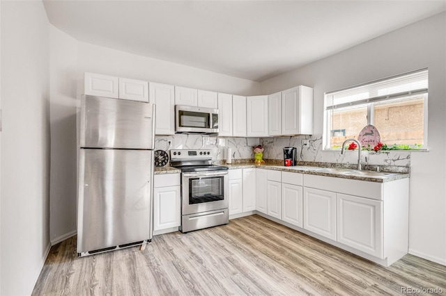 kitchen with stainless steel appliances, light wood-type flooring, decorative backsplash, and white cabinets