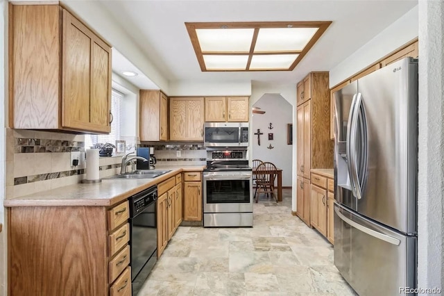 kitchen featuring stainless steel appliances, stone finish flooring, a sink, backsplash, and light countertops