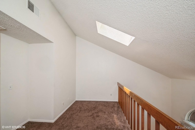 bonus room with dark colored carpet, a textured ceiling, and a skylight