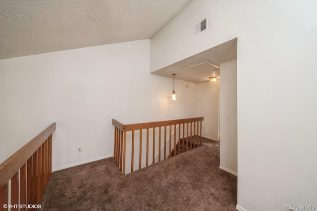 hall featuring a textured ceiling and dark carpet